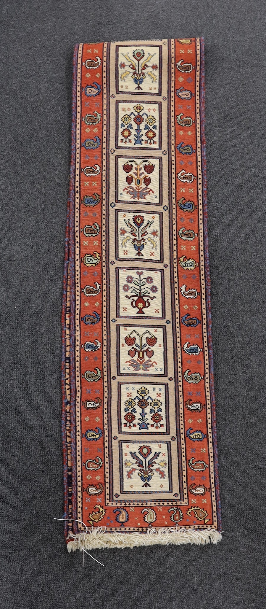 A Caucasian design red ground runner, approximately 250 x 35cm